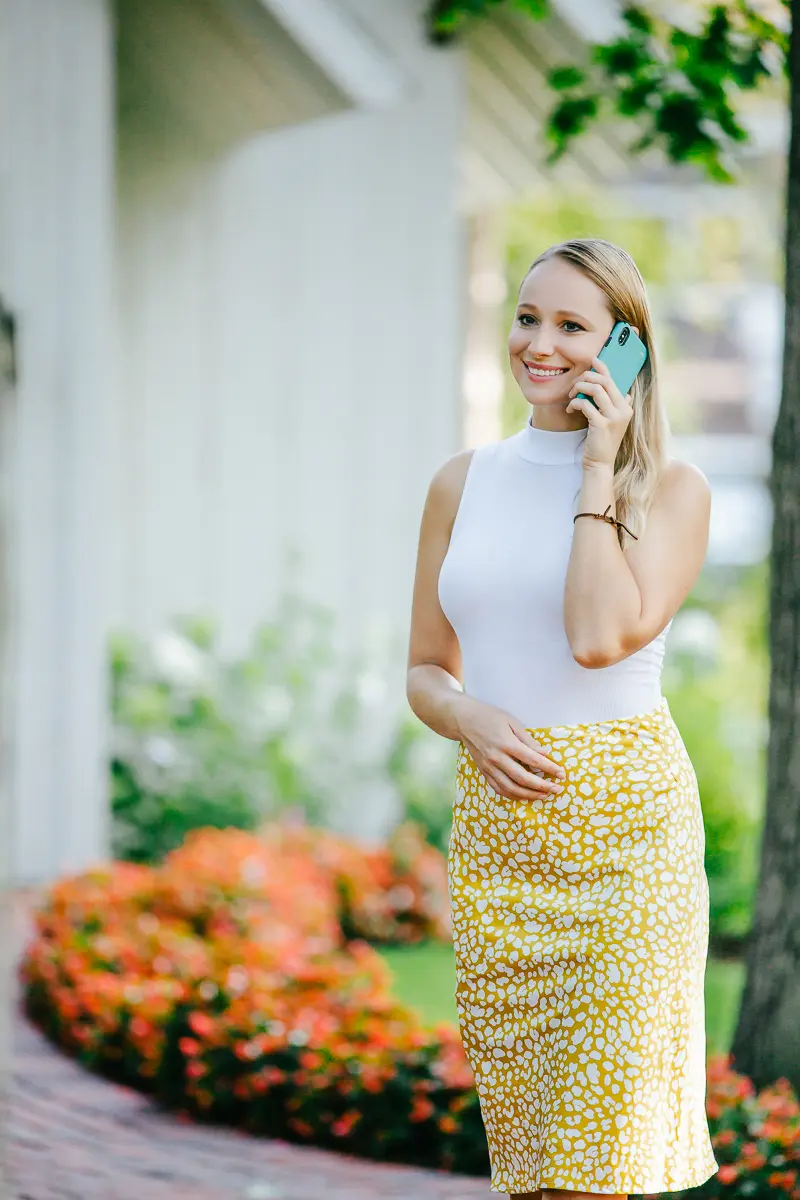 Elena smiling on her phone while walking outdoors