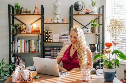Elena working on a laptop at her desk surrounded by plants and books