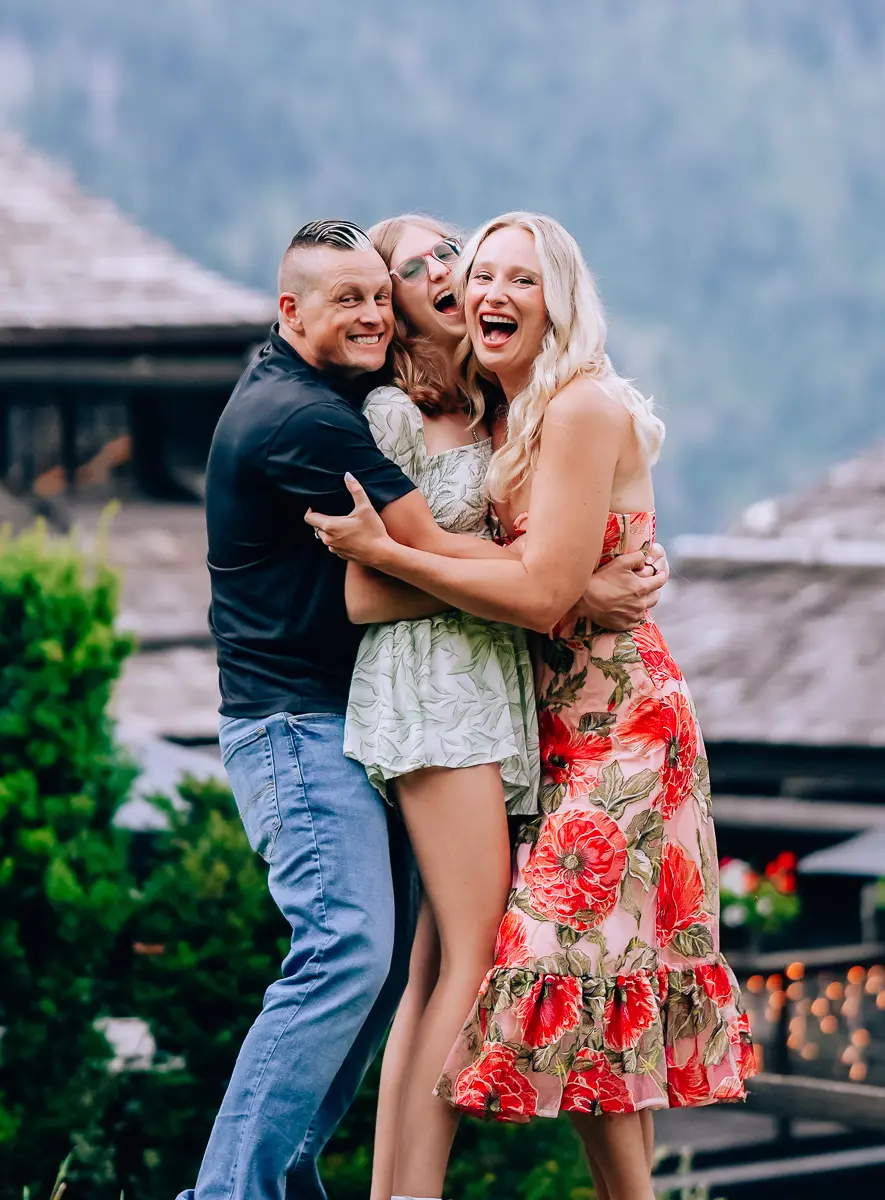 Elena, Joe, and Alexis laughing and hugging in the mountains