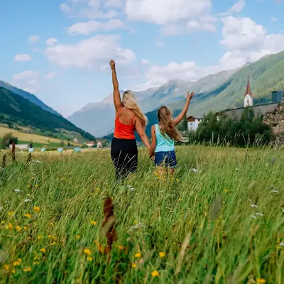 Elena and her daughter celebrating in a mountain meadow