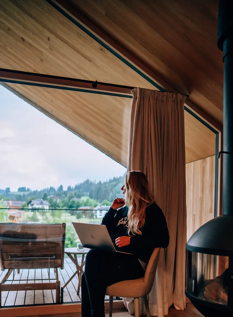 Elena working on her laptop inside a mountain cabin