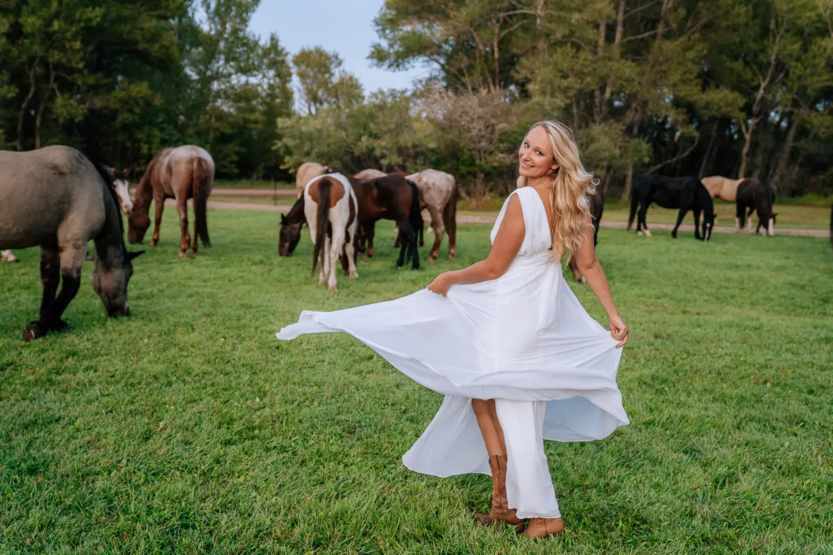 Elena in a white dress among horses